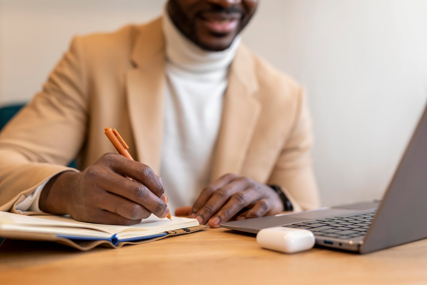 Professionnel rédigeant un document à côté de son ordinateur portable
